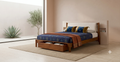 ALDER Storage Bed with warm walnut-toned solid rubberwood frame, beige chenille padded headboard, and footboard storage drawer open with linens inside
