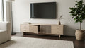 The Oslo Fluted TV Stand in light wood-look finish, with vertically fluted centre doors and four side drawers.