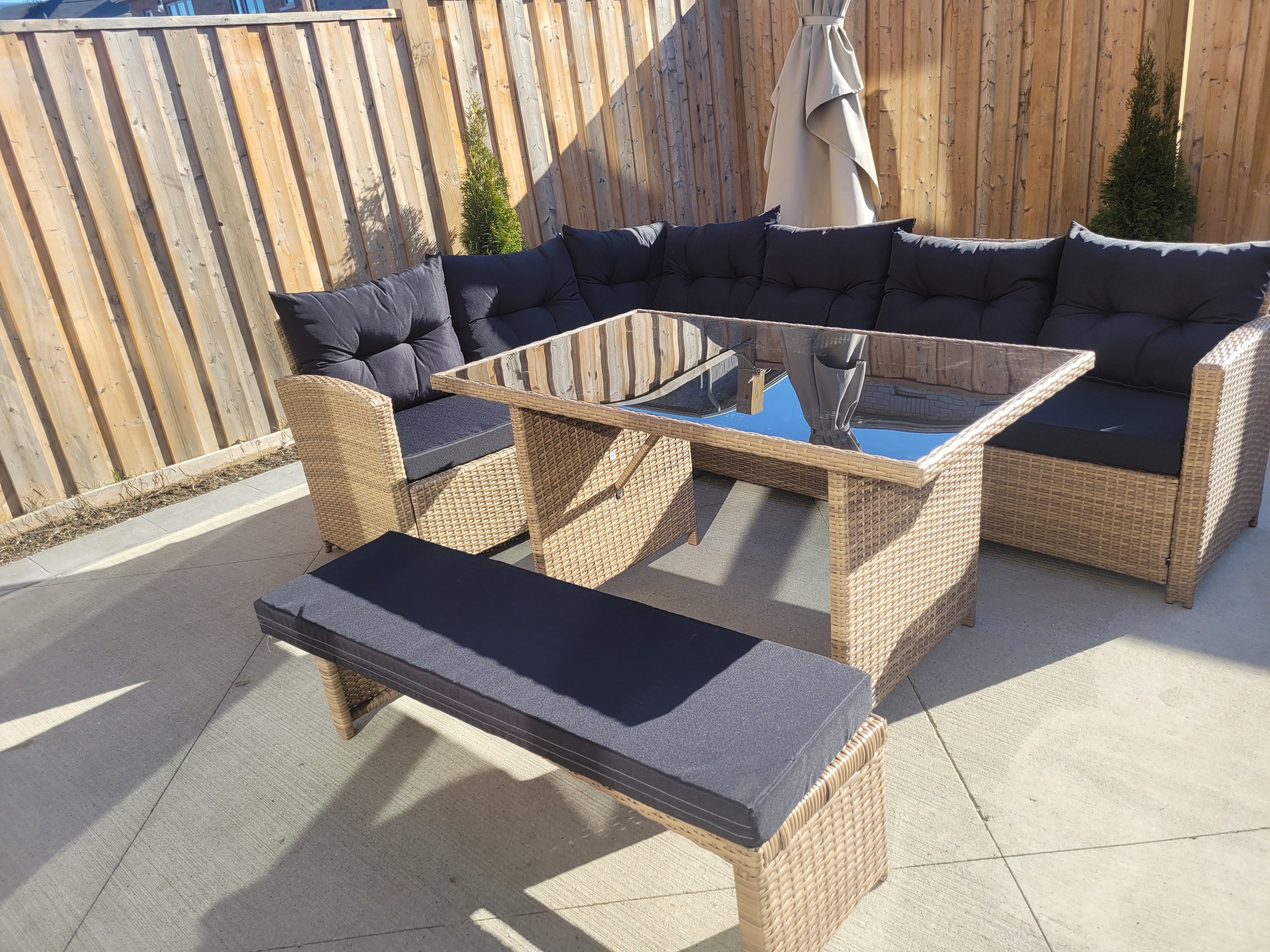 6-piece wicker outdoor patio set with beige wicker, black cushions, and glass dining table for backyard seating