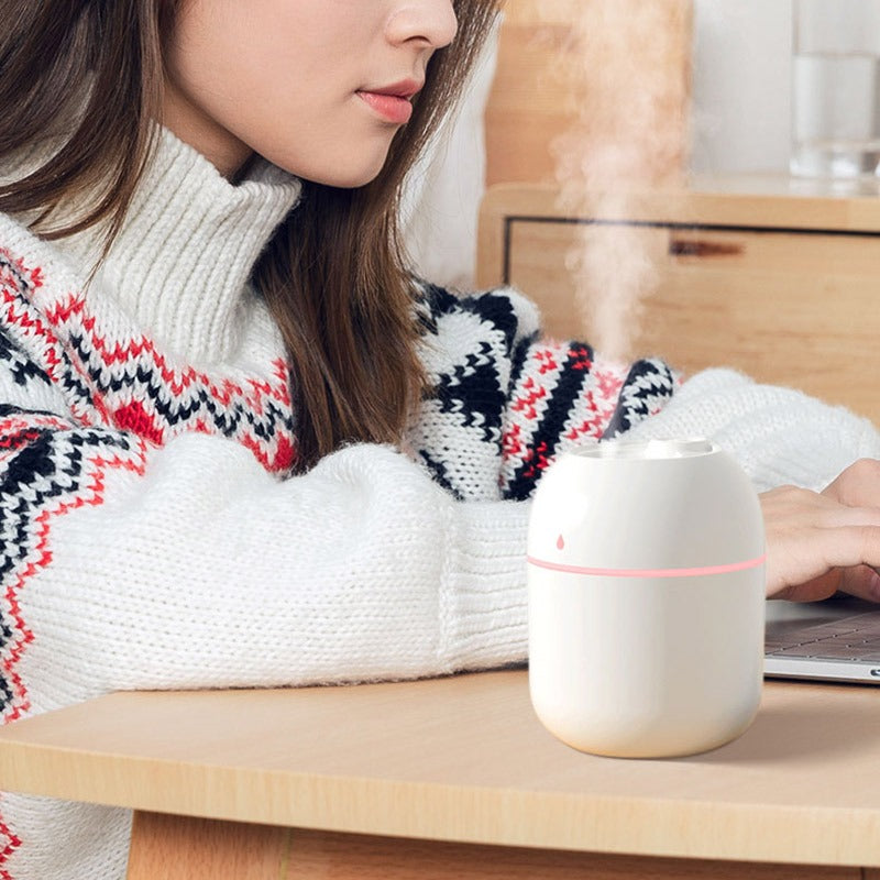 Mini humidifier with night light and USB charger on desk next to woman working on laptop